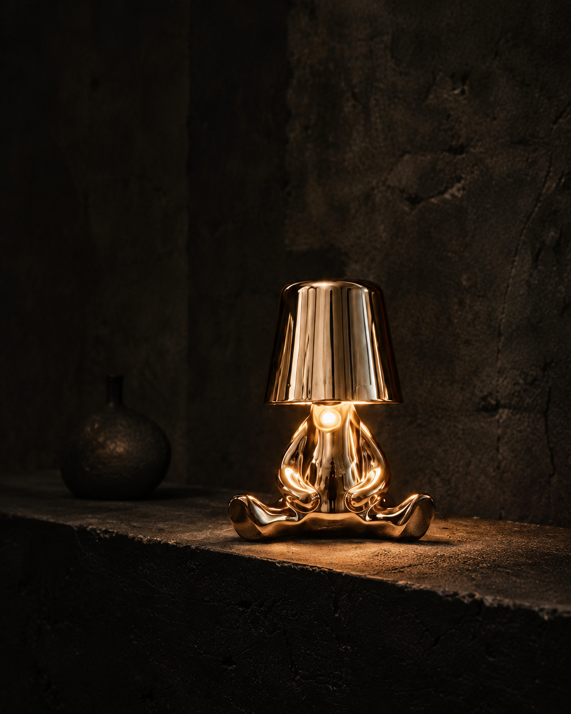Cross-legged GOLD FIGURES character lamp in a dark gallery interior